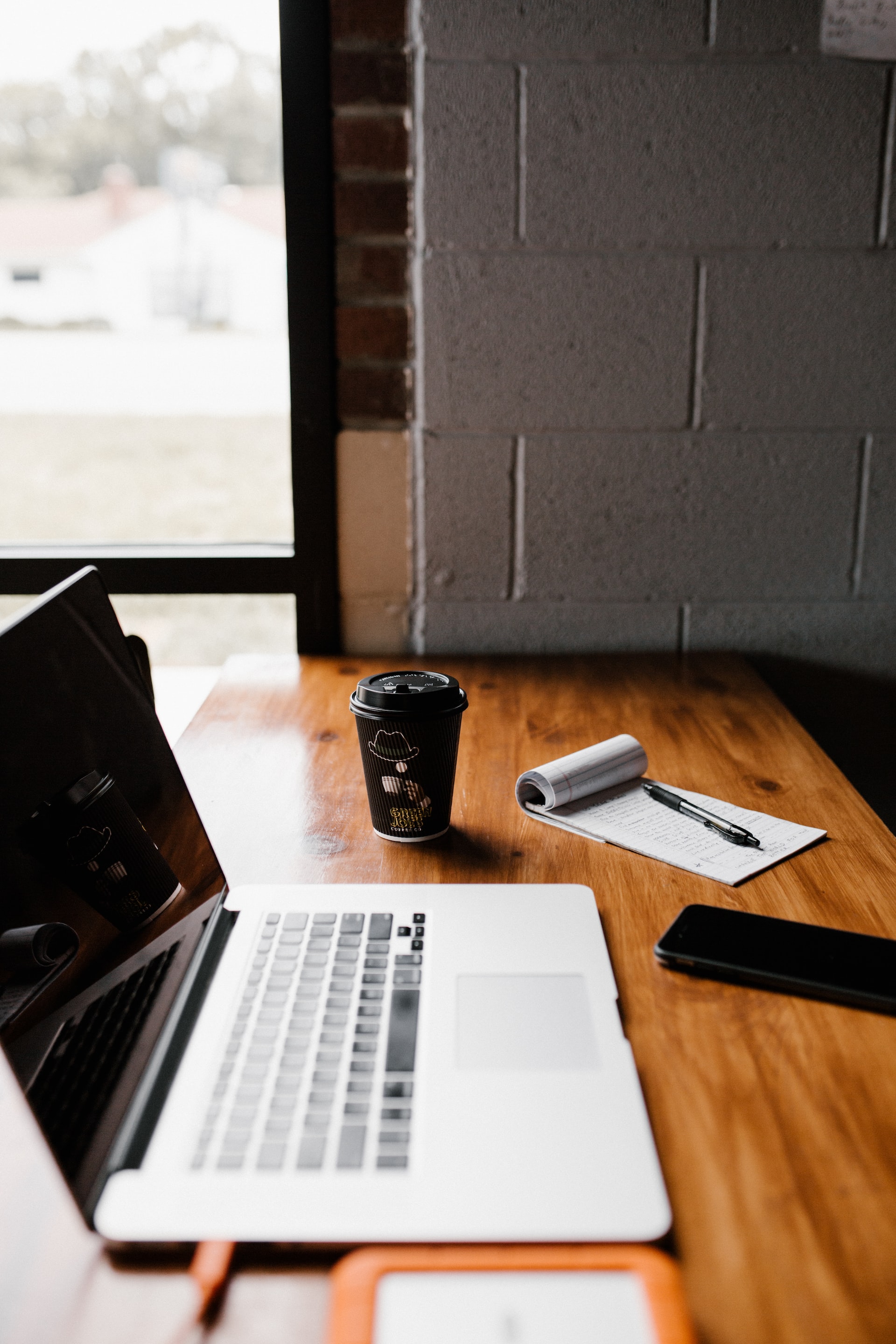 MacBook Pro, white ceramic mug,and black smartphone on table
